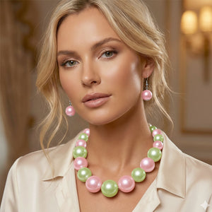 Light Pink and Green Oversized Graduated Pearl Glossy Statement Necklace Set on silver shown on a woman on a blurry background. 