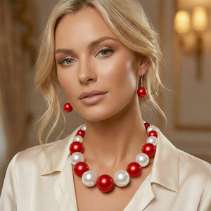 Red and White Oversized Graduated Pearl Glossy Statement Necklace Set on gold shown on a woman on a blurry background. 
