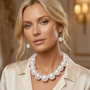 White Oversized Graduated Pearl Glossy Statement Necklace Set on silver shown on a woman on a blurry background. 