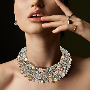 Model on a black background wearing Silver faceted beaded statement necklace set styled for evening or party wear with gold accents 
