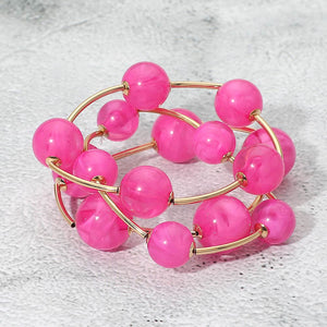 Fuchsia hot pink chunky ball 3-piece stretch bracelet set on gold displayed on a light textured background.