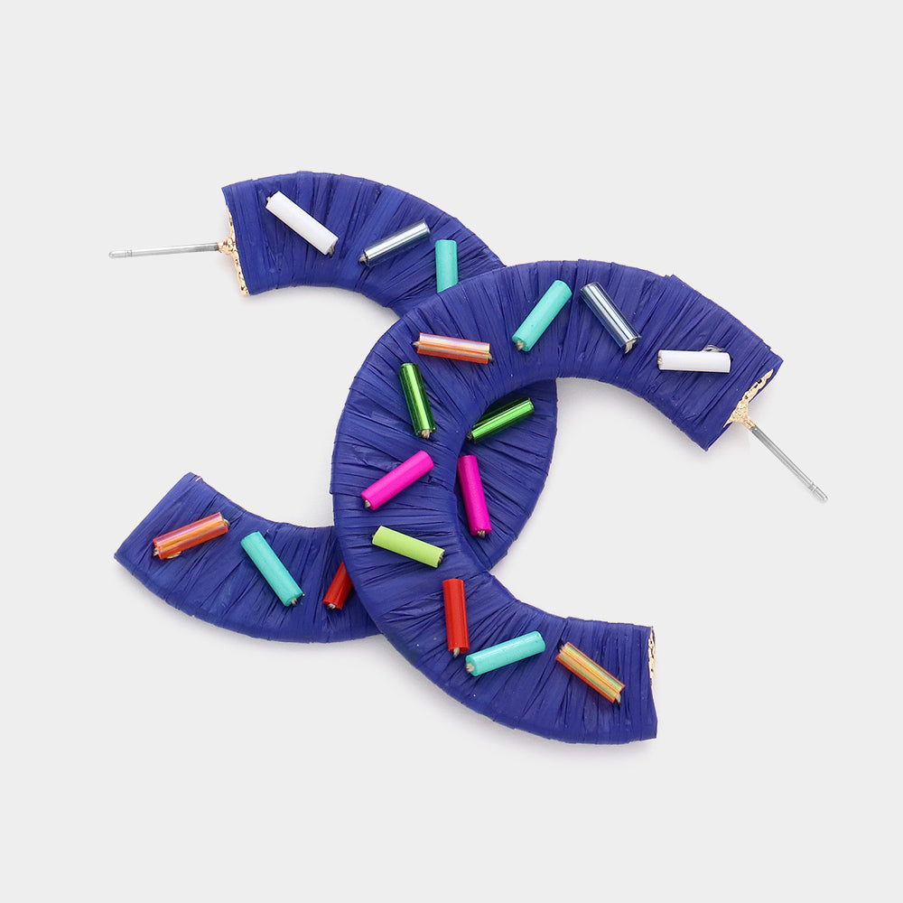 Multi Color Cylinders embellished onto a blue raffia wrapped half earring on a white background 1.75"