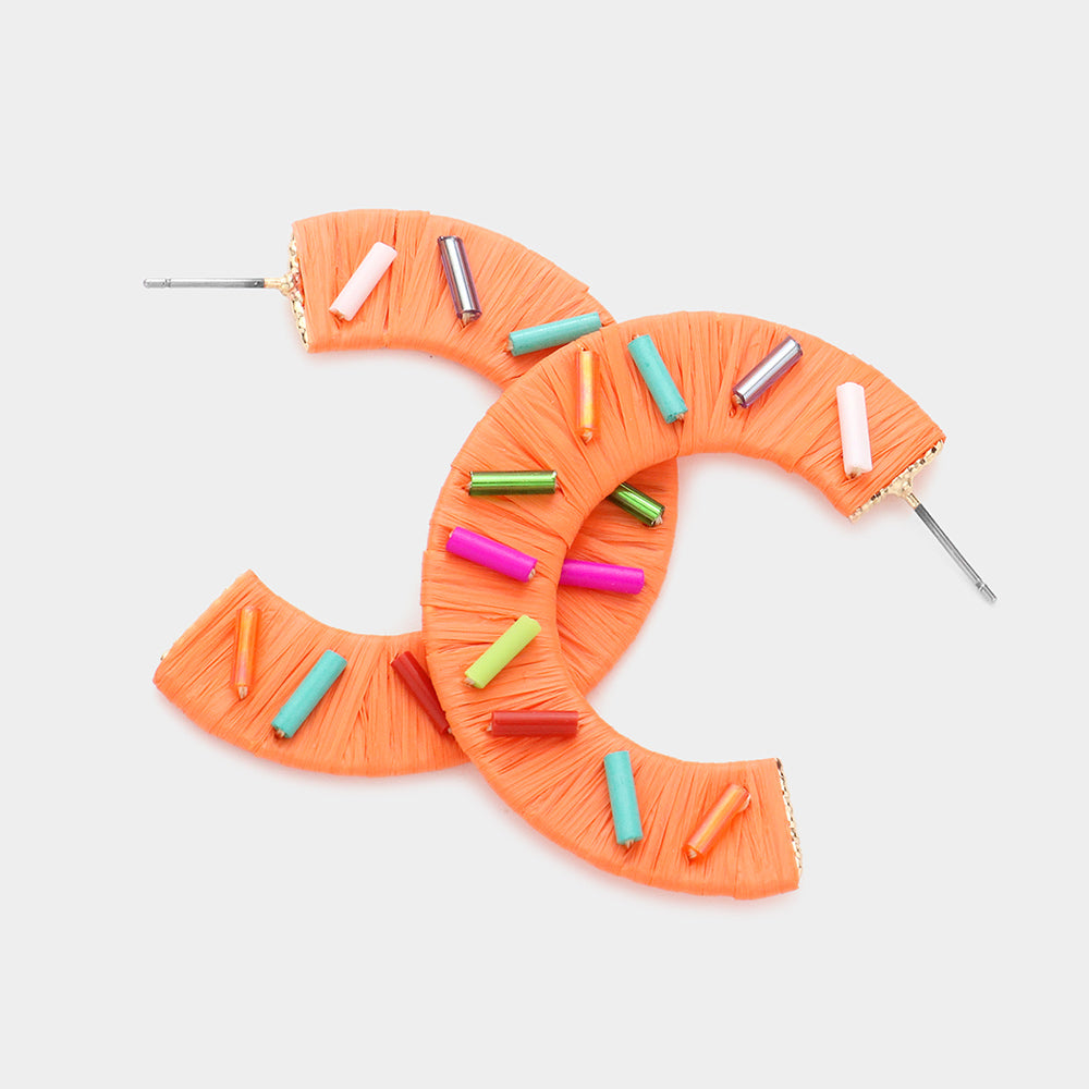 Multi Color Cylinders embellished onto a orange raffia wrapped half earring on a white background 1.75"
