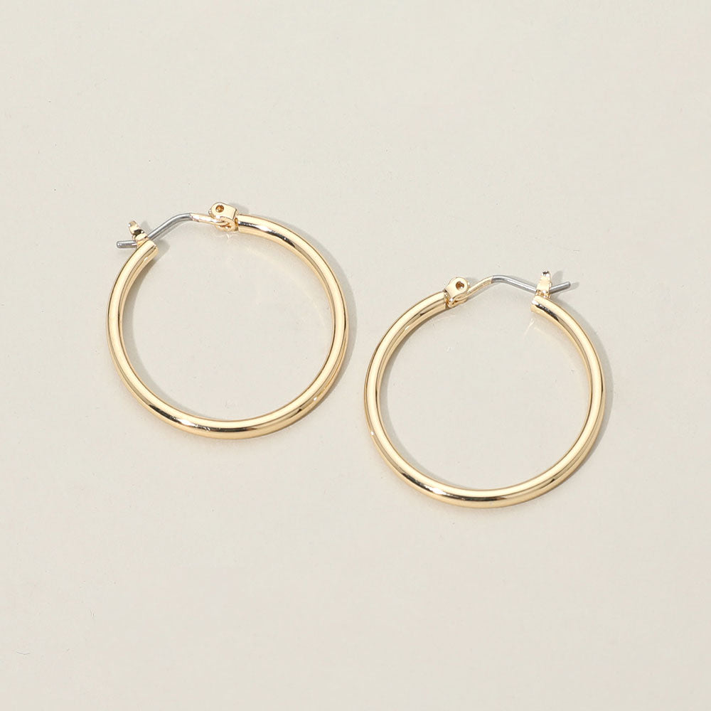 A pair of polished gold hoop earrings with silver-toned pin catch backings, displayed on a clean, light beige background.