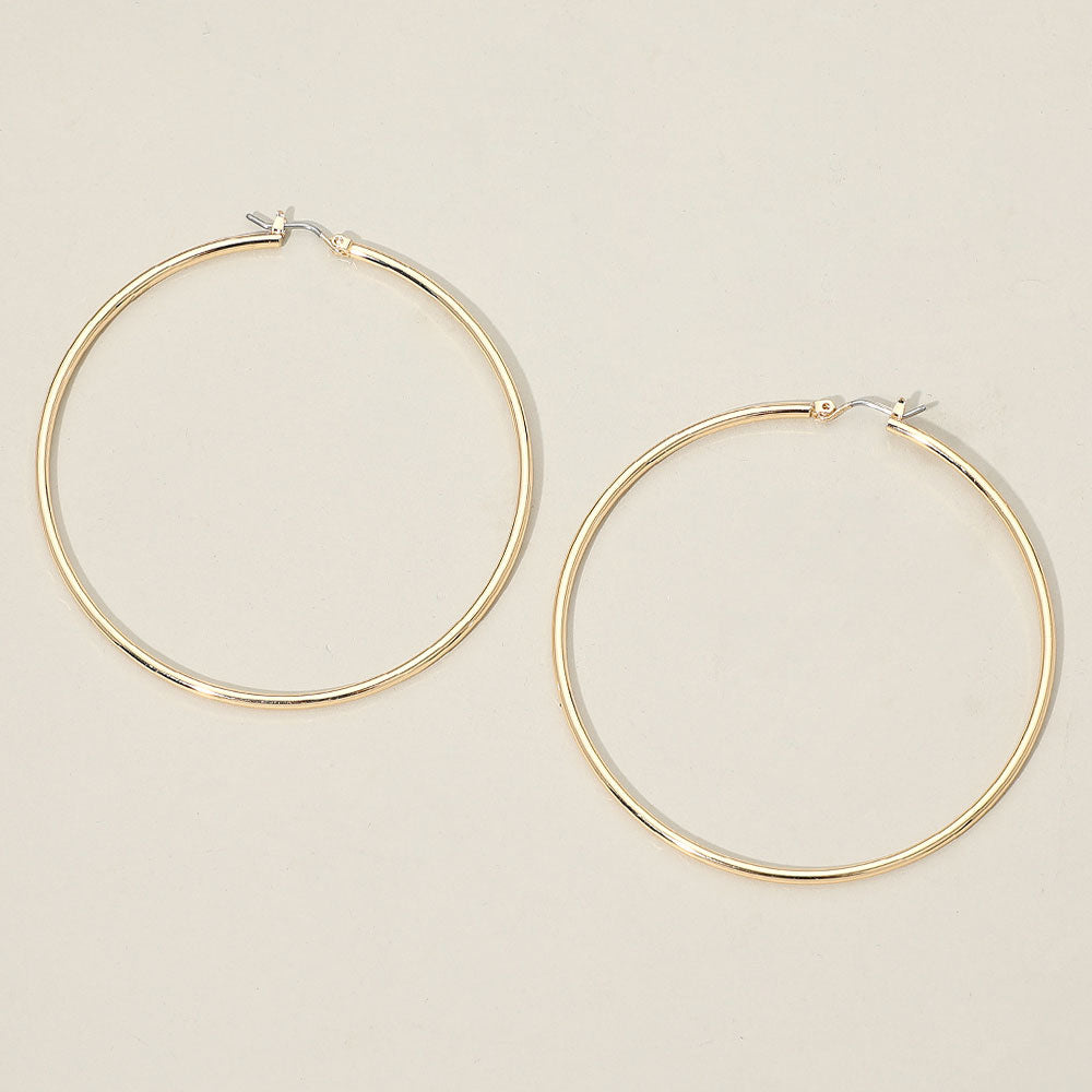 A pair of thin gold hoop earrings with simple pin catch backings, displayed on a light beige background.