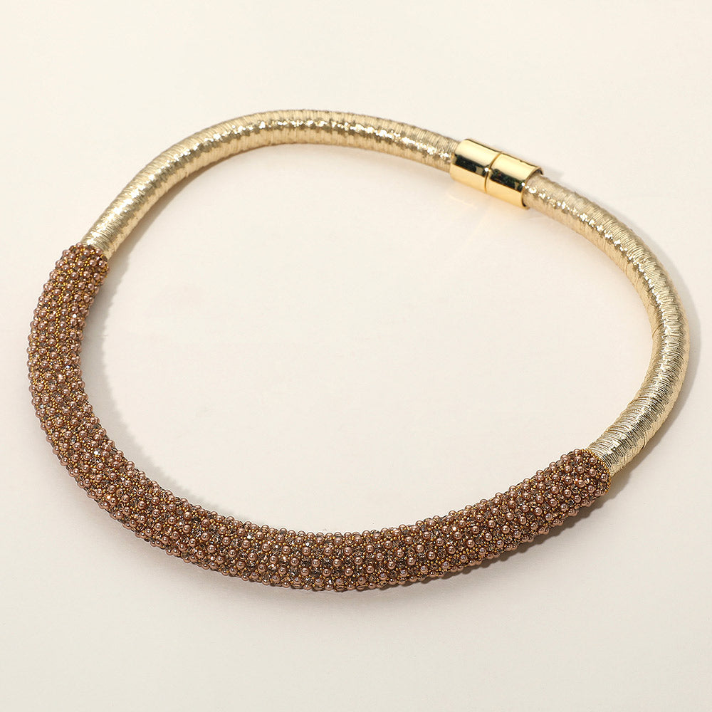 Gold Stone crystal beaded magnetic choker necklace on gold with a textured crystal-beaded front section, displayed on a light beige background.