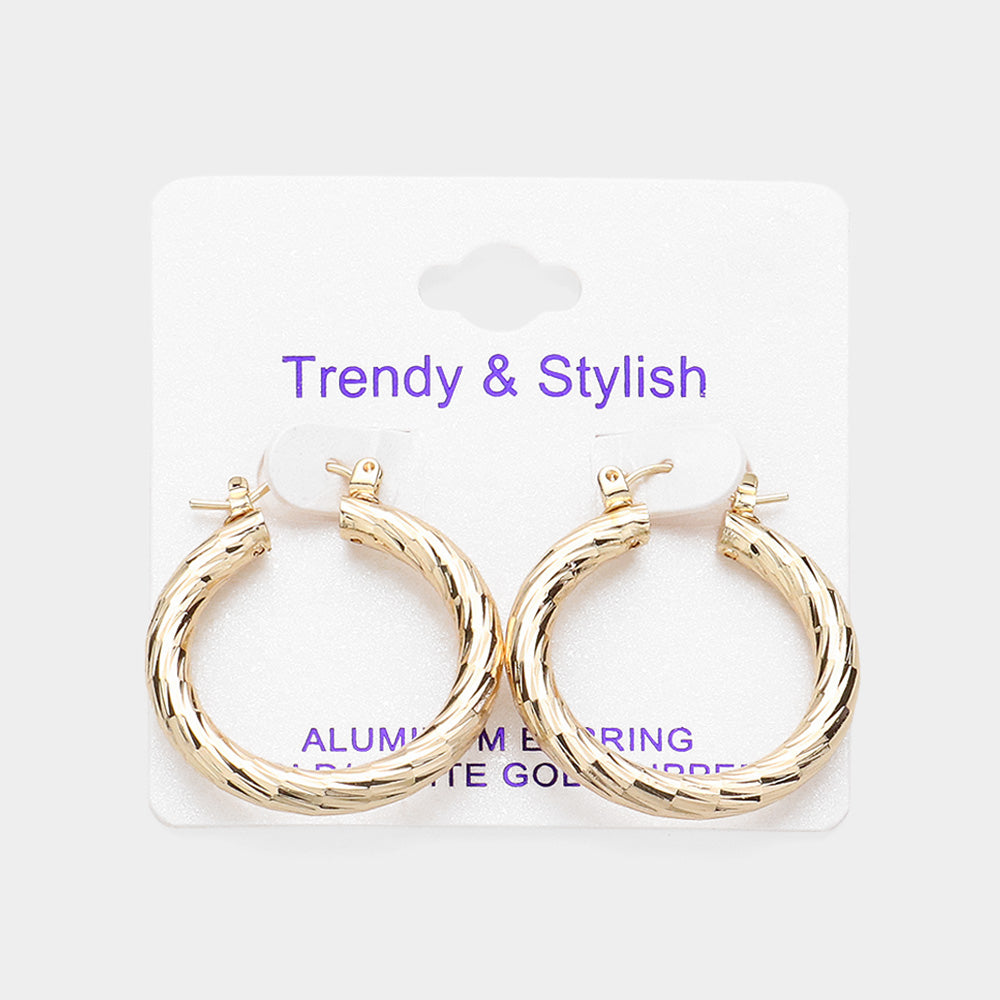 Gold-tone textured hoop earrings with a polished twisted design and pin catch closure, displayed on a white jewelry card against a light background.