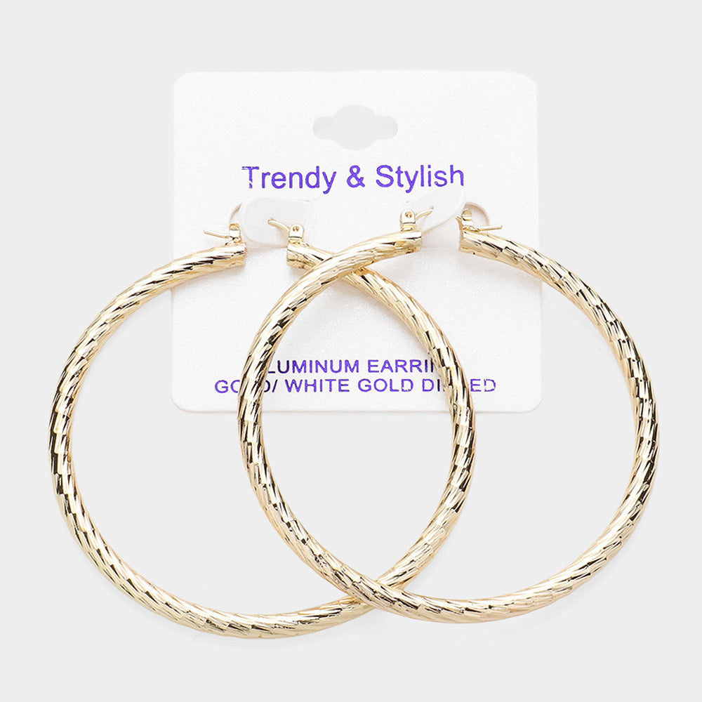A pair of large textured hoop earrings in a shiny gold finish, displayed on a white backing card with purple text that reads 'Trendy & Stylish' and 'ALUMINUM EARRINGS 