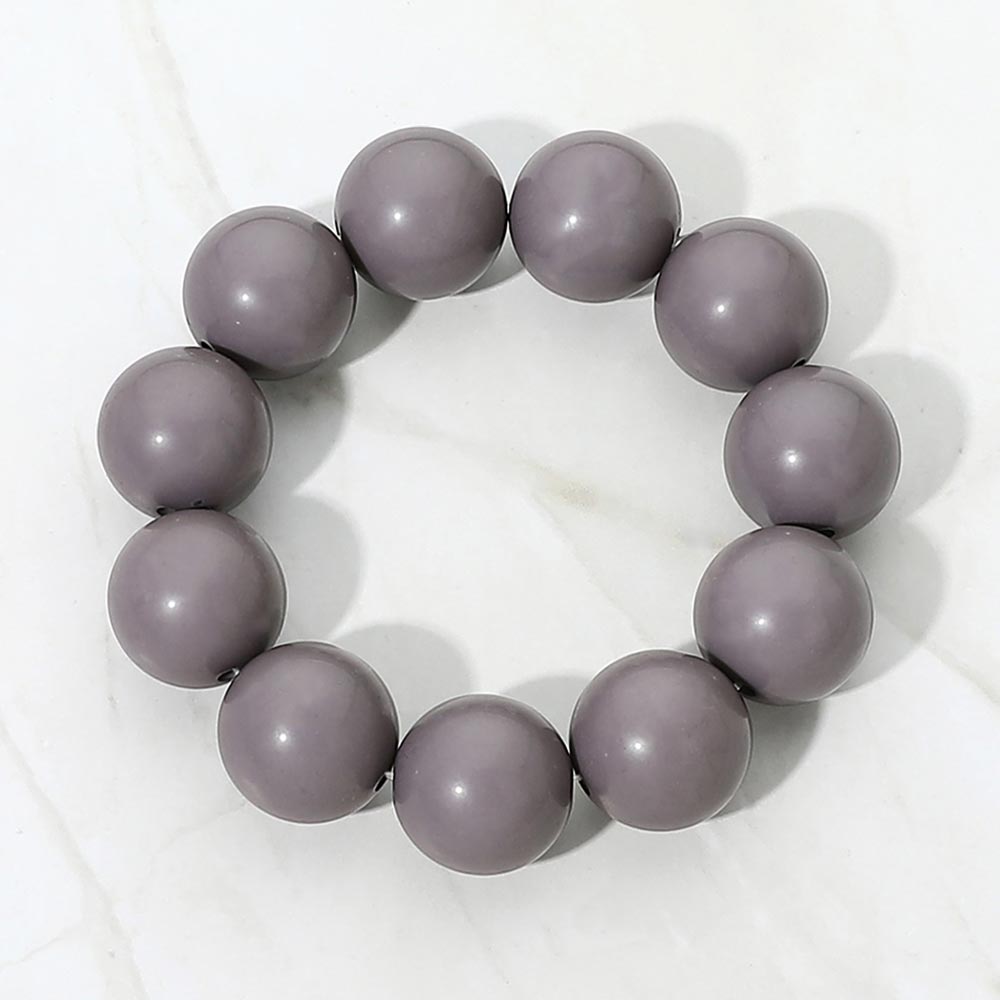 Gray chunky ball beaded stretch bracelet with oversized round beads, displayed on a white marble background.
