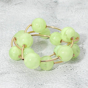 Light green chunky ball 3-piece stretch bracelet set on gold displayed on a light textured background.