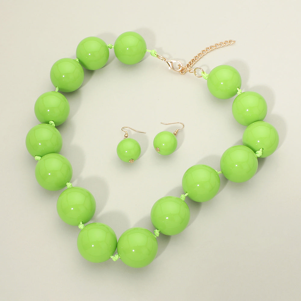 Lime Green chunky ball beaded statement necklace set with oversized round beads, matching drop earrings, displayed on a light cream background.