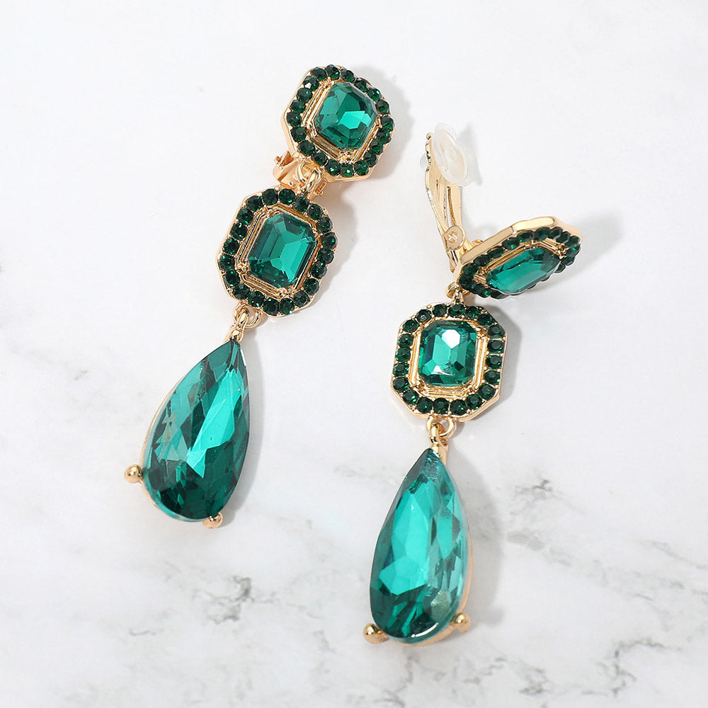 Emerald green crystal square and teardrop clip-on earrings on gold-tone metal, displayed against a white background.