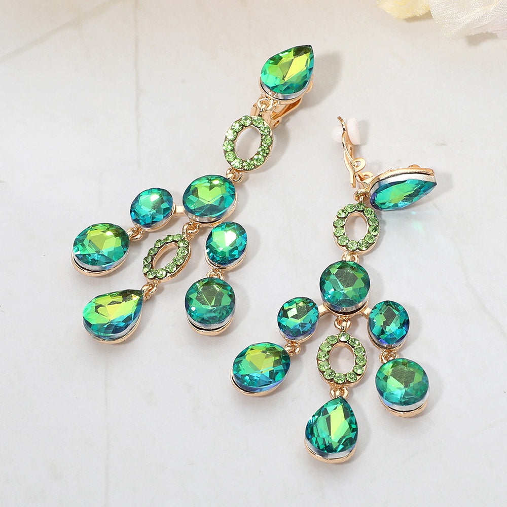Green faceted chandelier clip-on earrings with cascading dangle stones and gold-tone setting on a marble background