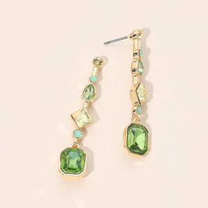 Green geometric crystal link drop earrings on gold with faceted stones on a beige background.