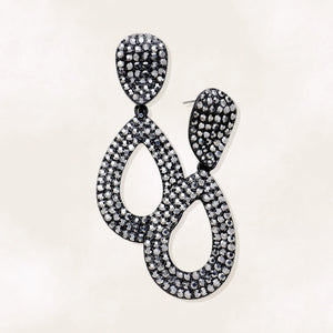 Gray rhinestone pavé cut out teardrop pageant earrings on black with smoky crystal sparkle on beige background.