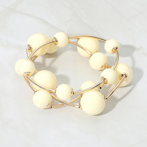 Ivory beaded stackable stretch bracelet set on gold on white marble background