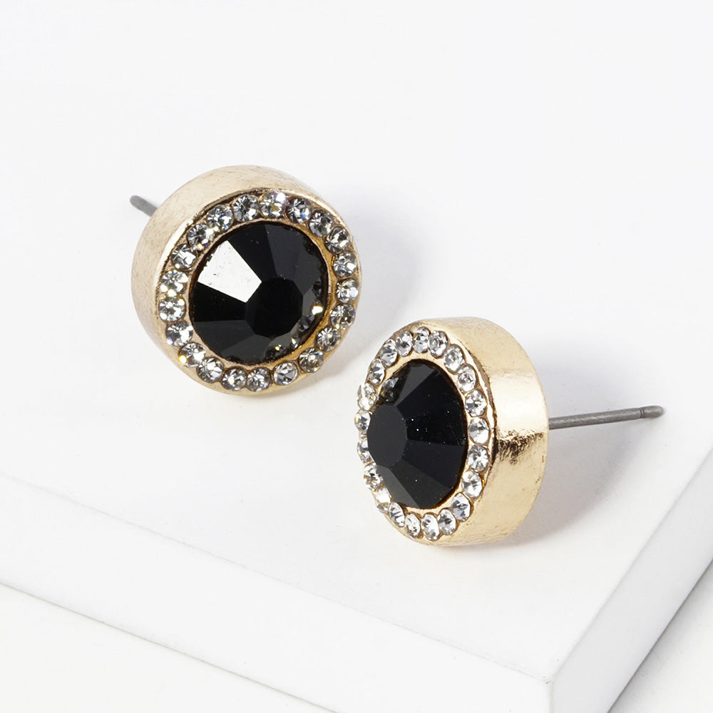 A pair of gold stud earrings with an oval jet black faceted center stone surrounded by a halo of small clear rhinestones, displayed on a clean white surface.