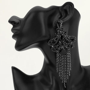 A large ornate Jet Black crystal statement earring with cascading bead fringe and clear crystal accents on a black earring mannequin.