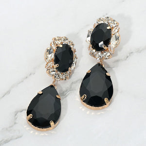 Jet black oval and teardrop earrings with clear crystal accents on gold on a white marble background