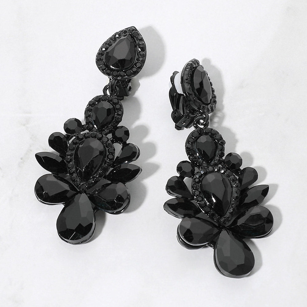 Black crystal chandelier clip-on earrings with teardrop and oval faceted stones surrounded by smaller clear rhinestones, displayed on a white marble surface.