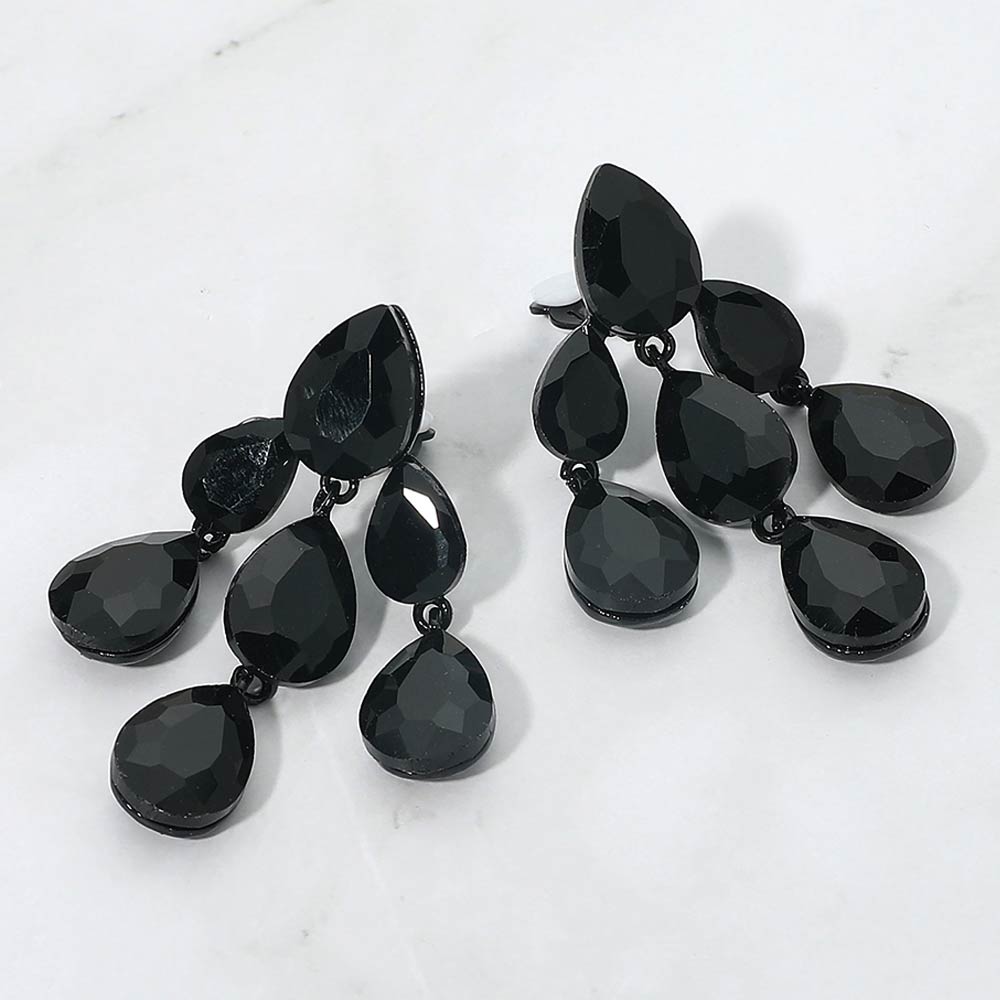 Jet black crystal teardrop cluster chandelier clip-on earrings on black on white marble background