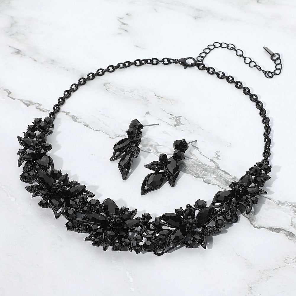 Black floral necklace and earrings set on a marble surface