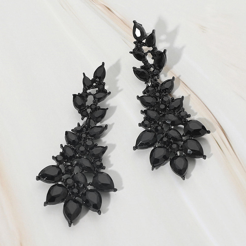 Jet black teardrop cluster drop earrings with faceted stones on black setting on white marble background