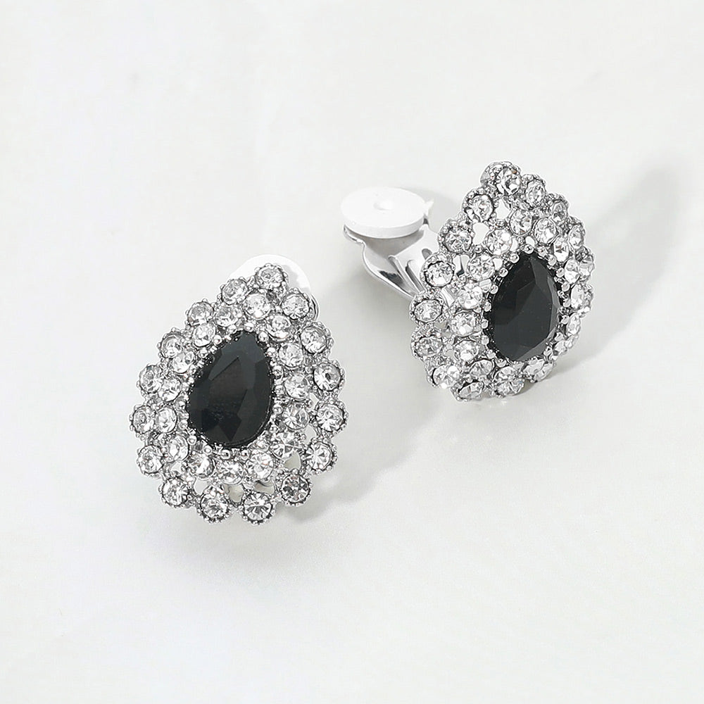 Jet black teardrop rhinestone halo clip-on earrings with silver-tone setting and crystal cluster design on a light gray background