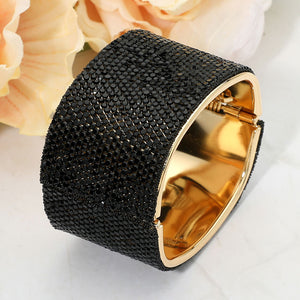 Jet black wide rhinestone hinged bangle bracelet with a chunky statement silhouette and polished gold-tone setting