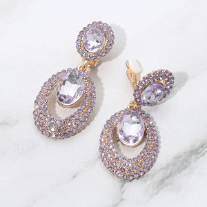 Lavender purple oval double-halo crystal clip-on earrings on gold on a white marble background — 2.1" statement drops for evening or pageant glam.