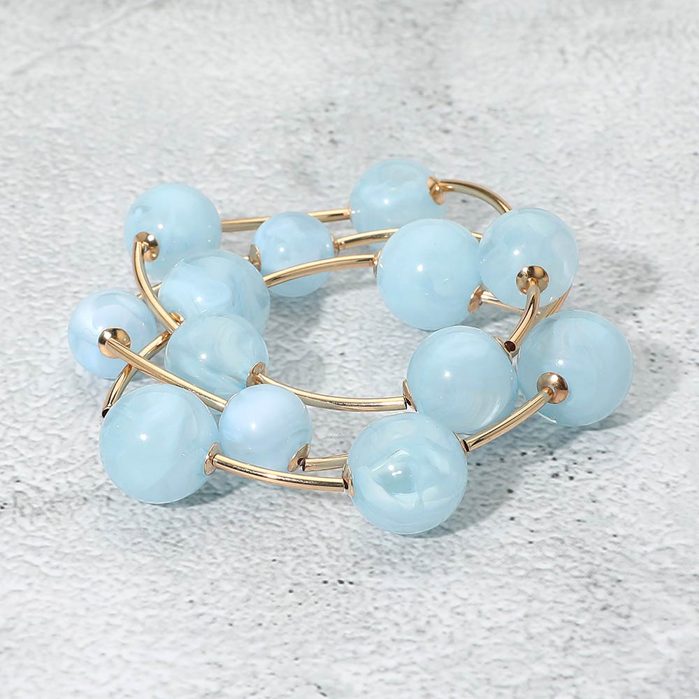 Light blue chunky ball 3-piece stretch bracelet set on gold displayed on a light textured background.