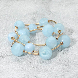 Light blue chunky ball 3-piece stretch bracelet set on gold displayed on a light textured background.