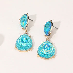 Aqua crystal glitter teardrop drop earrings on gold on light beige background