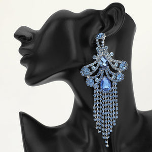 A large ornate Light Blue crystal statement earring on silver with cascading bead fringe and clear crystal accents on a black earring mannequin.
