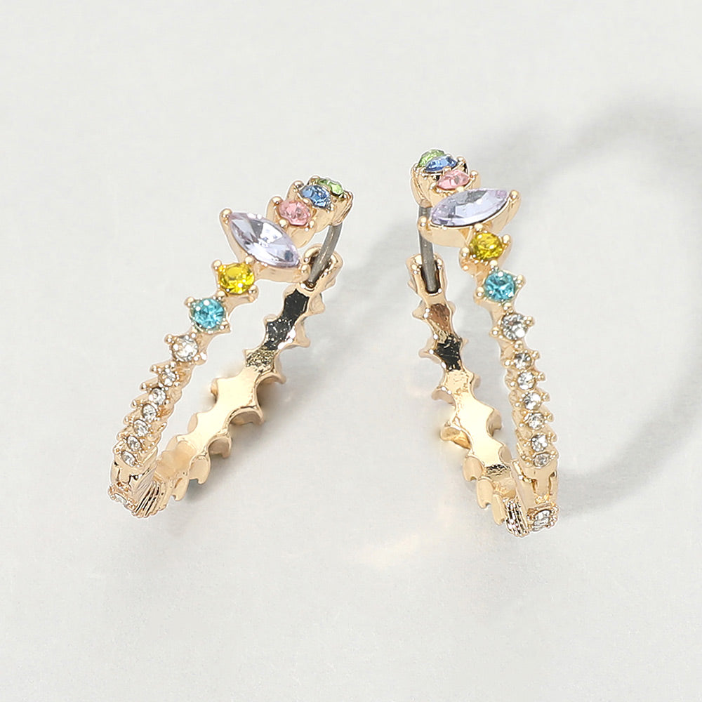 A pair of gold huggie hoop earrings with pastel multi-color marquise and round gemstones, displayed on a light gray background.
