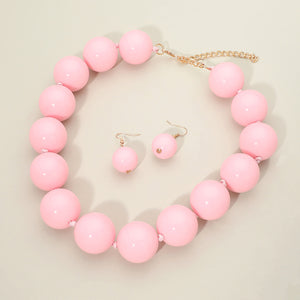 Light Pink chunky ball beaded statement necklace set with oversized round beads, matching drop earrings, displayed on a light cream background.