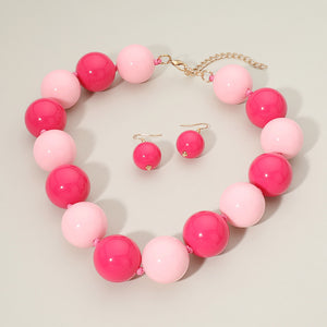 Hot Pink and Light Pink chunky ball beaded statement necklace set with oversized round beads and matching earrings, displayed on a beige background.
