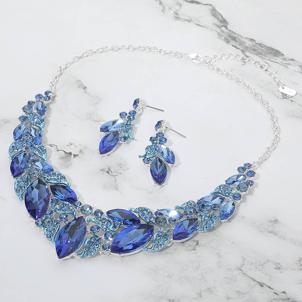 Light sapphire royal blue marquise leaf crystal necklace set on silver with matching earrings, elegant statement jewelry for prom and evening wear on a marble background