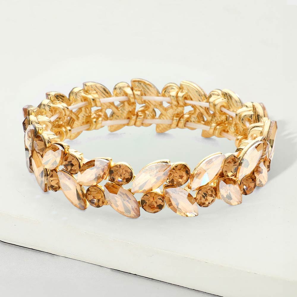 Gold stone light topaz marquise and round stone cluster stretch bracelet on gold on a white marble background