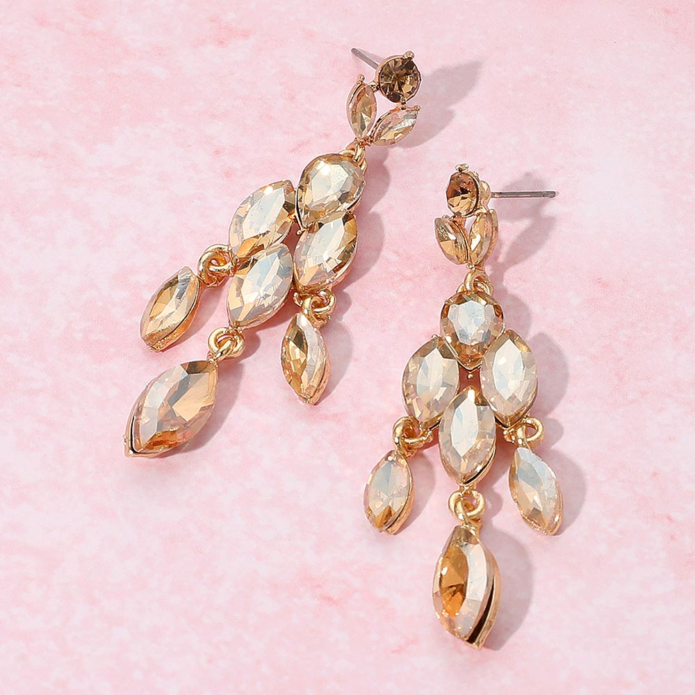 Gold and clear triple link crystal dangle earrings on a pink background