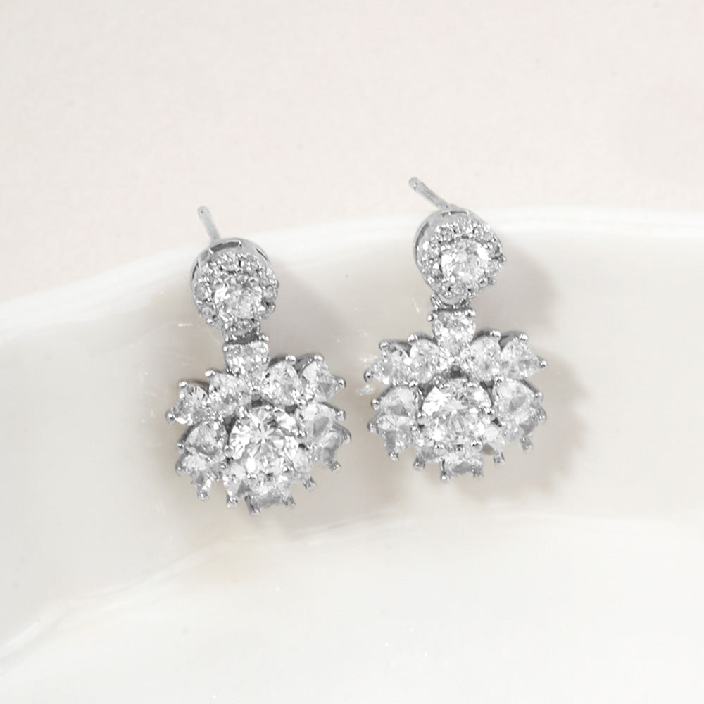 Little girls clear crystal drop earrings in a silver finish featuring round crystal studs and floral-inspired crystal clusters, displayed on a white jewelry stand.