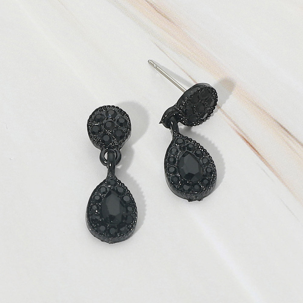 Little girls black crystal teardrop halo earrings on black displayed on a white marble background.