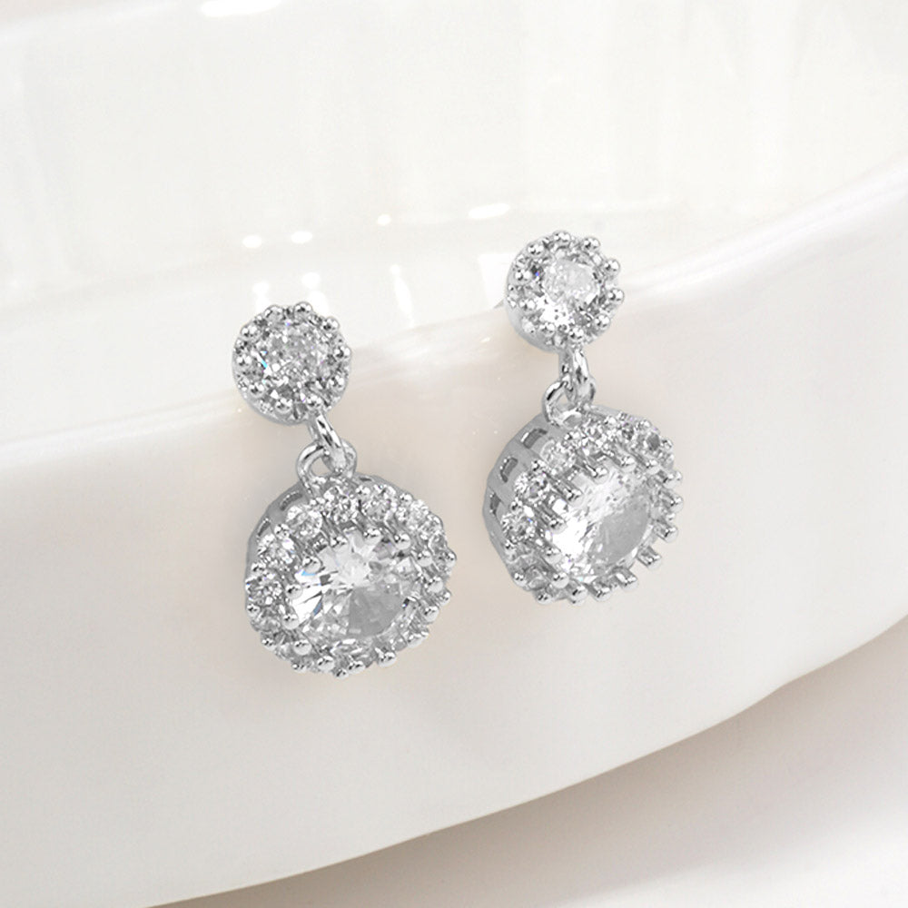 Clear crystal halo drop earrings on silver for little girls featuring a round crystal surrounded by a sparkling halo with a petite crystal teardrop, displayed on a white background.
