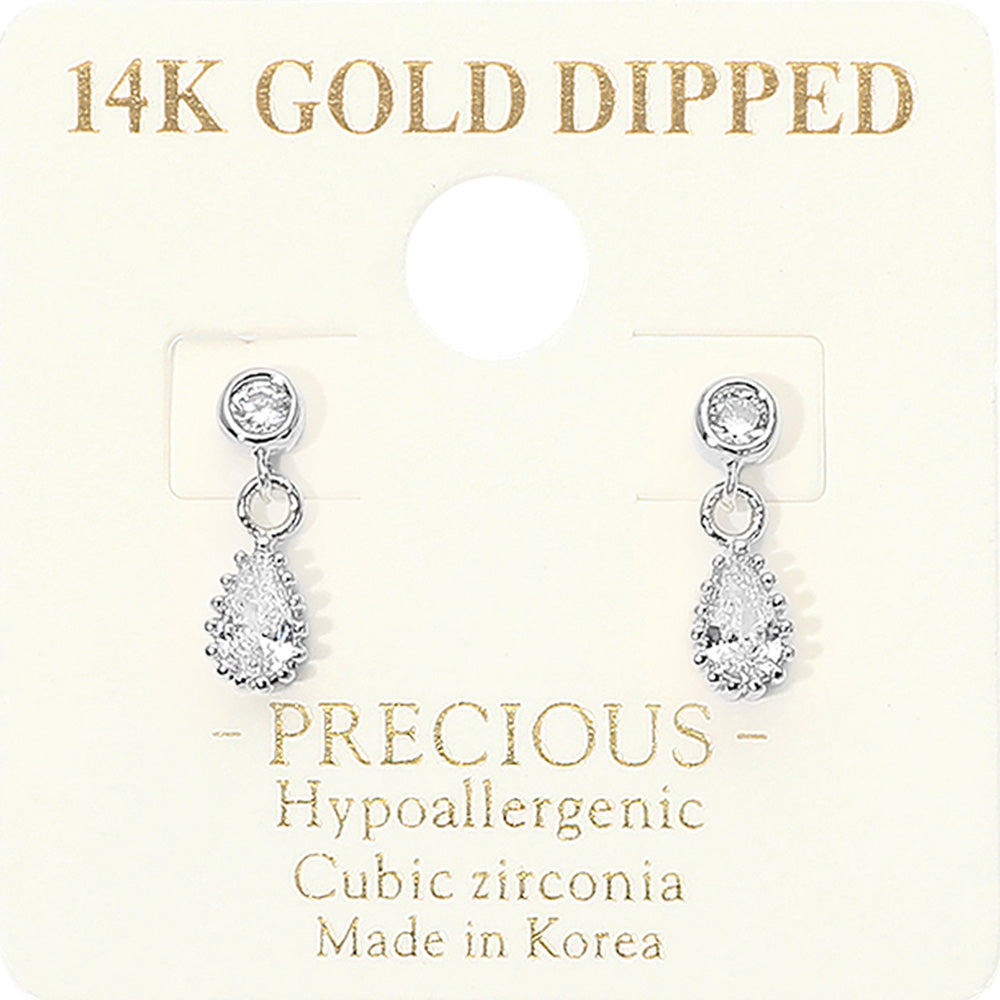A pair of 14K gold-dipped cubic zirconia dangle earrings on a cream-colored display card. The earrings feature a silver-tone setting with a round clear stone and a teardrop-shaped clear stone below, presented on a card with gold text detailing.
