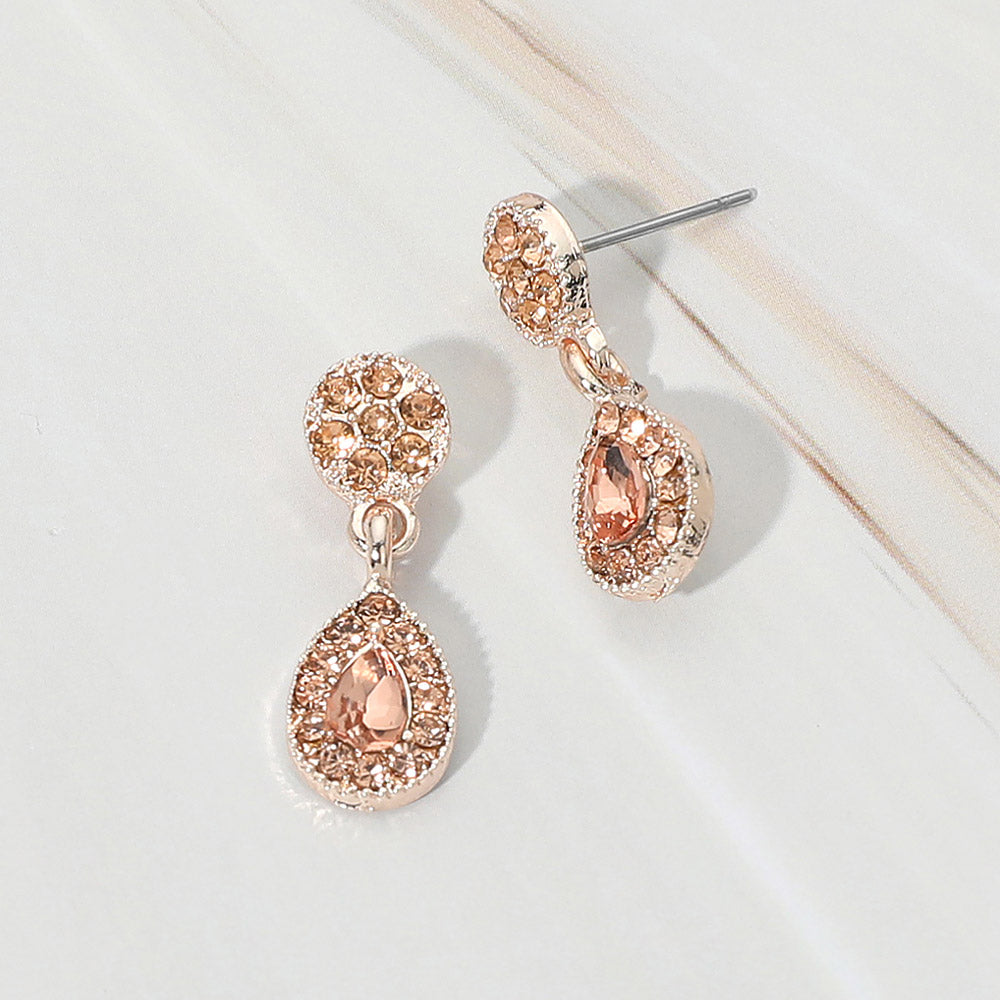 Little girls peach crystal teardrop halo earrings on rose gold displayed on a white marble background.