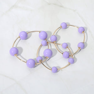 Lavender beaded stackable stretch bracelets on gold, shown here laid out individually on white marble background
