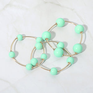 Mint beaded stackable stretch bracelets on gold, shown here laid out individually on white marble background