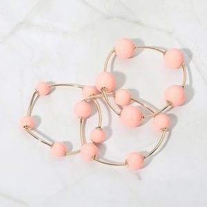 Peach beaded stackable stretch bracelets on gold, shown here laid out individually on white marble background