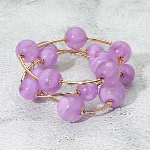 Lavender chunky ball 3-piece stretch bracelet set on gold displayed on a light textured background.