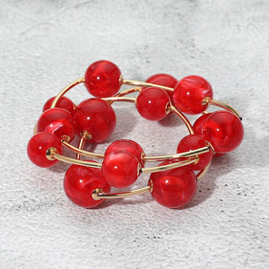 Red chunky ball 3-piece stretch bracelet set on gold displayed on a light textured background.